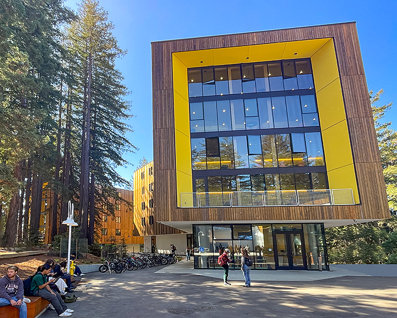 Residence halls at Kresge College surrounded by redwood trees under a clear blue sky