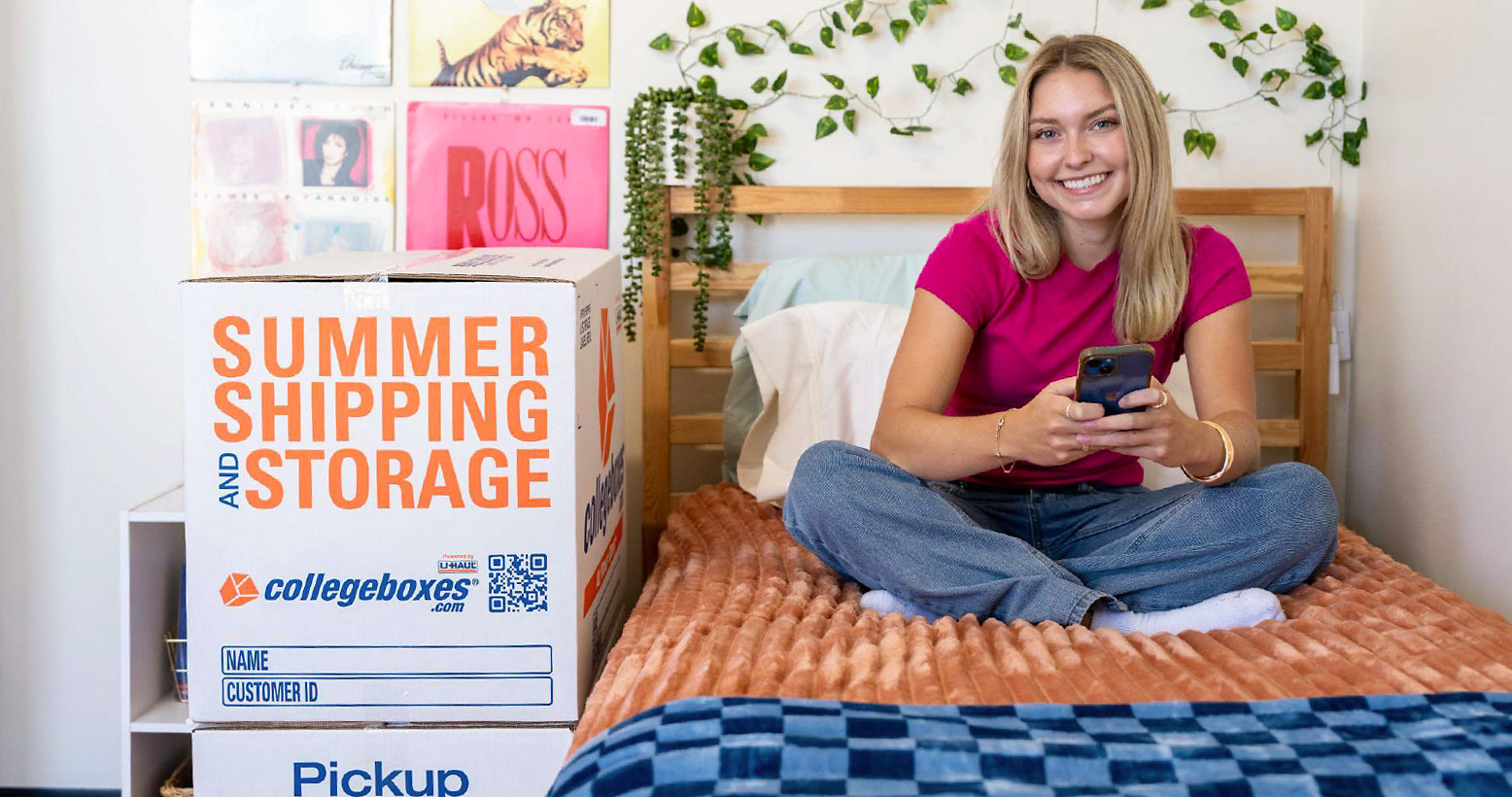 Student sitting on bed with summer storage boxes