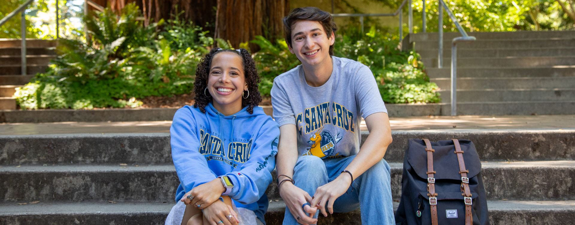 Two students smiling and sitting on stairs