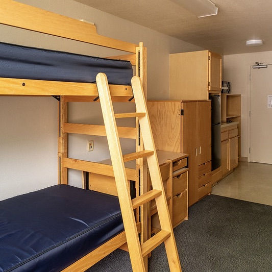 Triple room with bunk beds showing kitchenette in the background